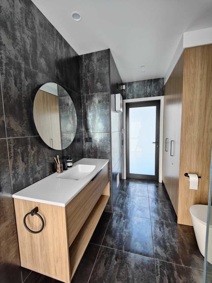 Photo of property: Enjoy a full sized, luxury tiled bathroom with the laundry tucked away behind cupboard doors. The bathroom doubles as an ensuite to the master bedroom.