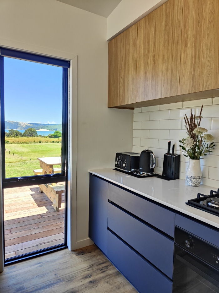 Photo of property: You won't miss the view even if you're cooking in the kitchen. Gorgeous views towards the giant sand dunes of Hokianga Heads.